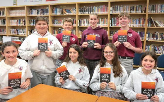 Seventh graders at Our Lady of Lourdes School in Slidell, La., pose for a photo with the book "A Long Walk to Water," a nonfiction novel by Linda Sue Park. (CNS/Clarion Herald/Beth Donze)