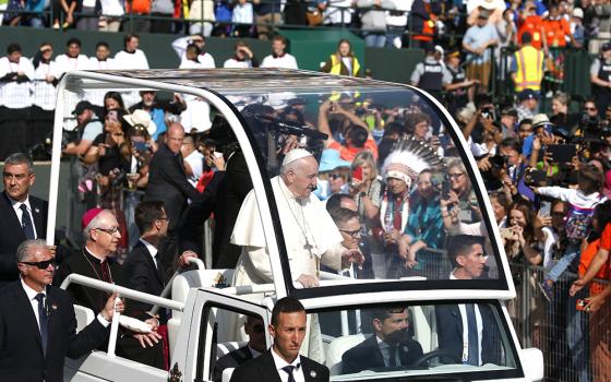 Pope Francis arrives to celebrate Mass at Commonwealth Stadium July 26 in Edmonton, Alberta, Canada. Looking on in the background with headdress is Phil Fontaine, former national chief of the Assembly of First Nations. (CNS/Paul Haring)