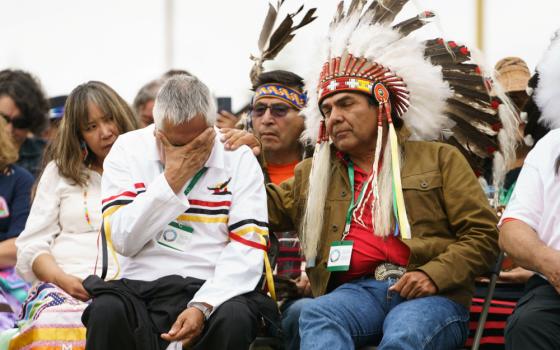 A man is comforted by an Indigenous leader during ceremonies in Maskwacis, Alberta, July 25, 2022, where Pope Francis apologized to Canada's native people on their land for the church's role in schools where Indigenous children were abused. (CNS photo/Ada