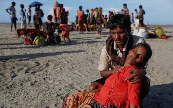 A man who said his village was burned and relatives killed by Myanmar soldiers comforts his wife as Rohingya refugees arrive by a wooden boat from Myanmar in Shah Porir Dwip, Bangladesh, Oct. 1, 2017. 