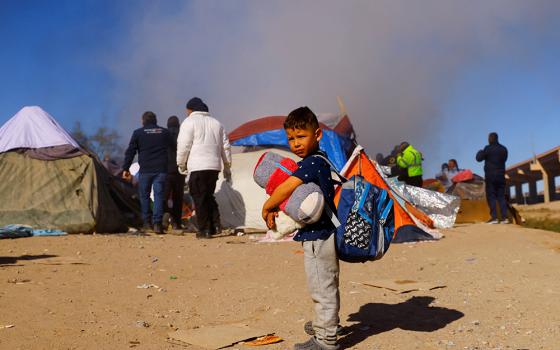 A child in Ciudad Juárez, Mexico, stands as police remove Venezuelan migrants from a camp on the banks of the Rio Grande Nov. 27, 2022. (CNS/Reuters/Jose Luis Gonzalez)