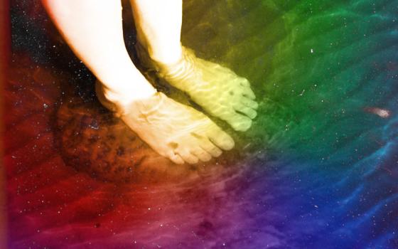 Feet standing in water with a rainbow hue (Maxwell Kuzma)