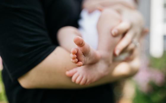 Photo illustration of a woman holding a baby (Unsplash/Wes Hicks)