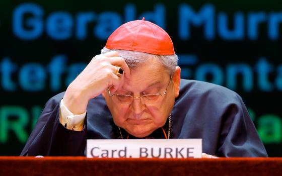 U.S. Cardinal Raymond Burke follows the written text of another speaker at the conference "The Synodal Babel" at the Ghione Theater in Rome Oct. 3. (CNS/Lola Gomez)