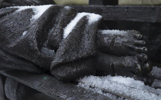 The "Homeless Jesus" sculpture by Timothy Schmalz is seen covered with snow outside Catholic Charities of the Washington Archdiocese Dec. 16, 2020. (CNS/Tyler Orsburn)