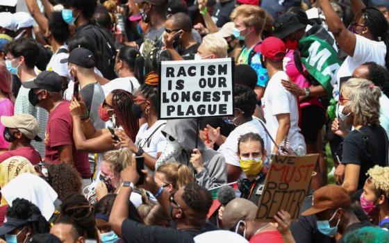 Protesters stand with a sign reading "Racism Is Our Longest Plague" in Washington Aug. 28, 2020, during the "Get Your Knee Off Our Necks" Commitment March on Washington 2020 in support of racial justice. 