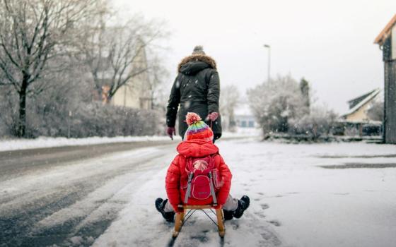 A person pulls another person on a sled. 