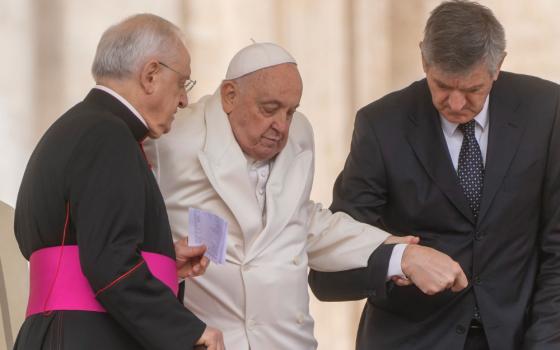 Pope Francis assisted while walking by prelate and aide