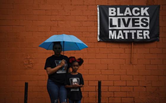 Brittany Elmore of Houston poses for a photo with her daughter Brooklyn near a "Black Lives Matter" sign May 23, 2021.