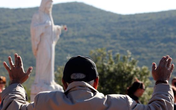 A man prays near a statue of Mary on Apparition Hill in Medjugorje, Bosnia-Herzegovina, in this Oct., 8, 2010, file photo. Pope Francis has decided to allow parishes and dioceses to organize official pilgrimages to Medjugorje; no decision has been made on the authenticity of the apparitions. (CNS photo/Matko Biljak, Reuters) 