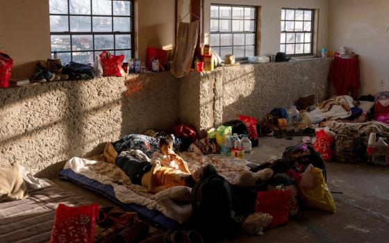 Man and girl lay on mattress in a sun-lit, earthen room. 