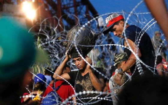 Young men framed by coils of barbed fencing. 