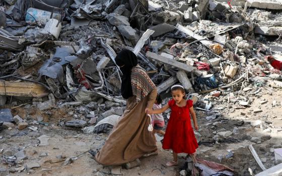 Woman and child step gingerly though rubble