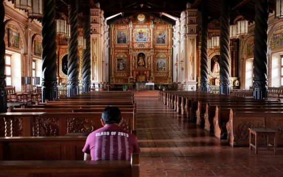 Ornate sanctuary pictured, with man in pew. 