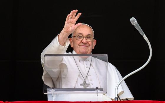 Pope Francis, smiling, waves from St. Peter's Square balcony