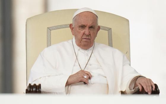 Pope Francis, seated, scowls.