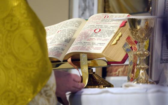 Altar shown up close, as well as priest's hands and vestments. 