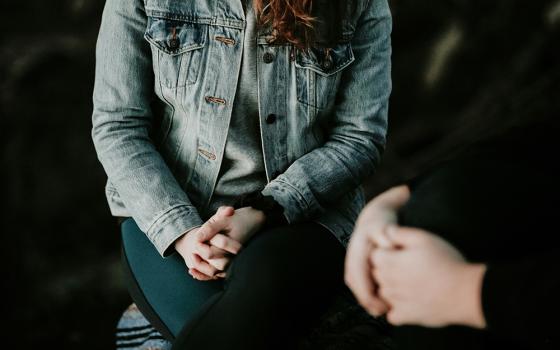 Two people sit with hands folded. (Unsplash/Priscilla Du Preez)