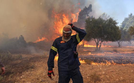 A firefighter walks next to rising flames as a wildfire burns near the village of Vati, on the island of Rhodes, Greece, July 25, 2023. Extreme heat waves in summer 2023 saw Greece, Italy and Spain record all-time high temperatures with the heat index in several Middle Eastern countries reaching 152 degrees Fahrenheit, near the limit of human survival. (OSV News photo, Nicolas Economou, Reuters)