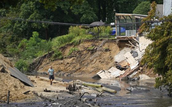 Man walks though enormous washed out gully.