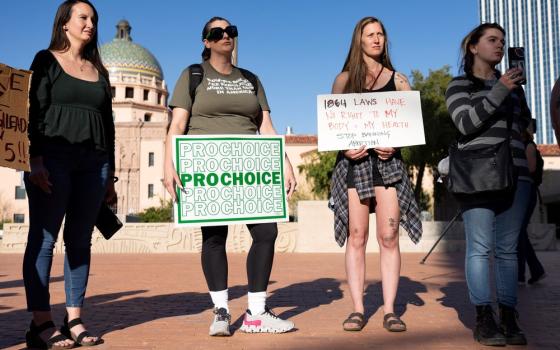 Four women stand holding signs. 