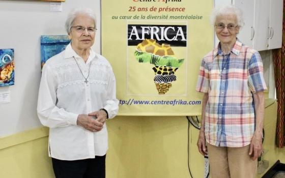 Srs. Monique Bonnefoy, left, and Rita Toutant of the Missionary Sisters of Our Lady of Africa stand near a sign that reads "25 years at the heart of Montreal's diversity" at Centre Afrika. The two ministered many years in Africa and now minister at the intercultural center in Montreal. (GSR photo/Joanna Kozakiewicz)