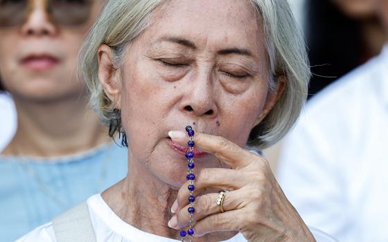 A woman prays as she awaits Mass with Pope Francis at Gelora Bung Karno Stadium in Jakarta, Indonesia, Sept. 5. (CNS/Lola Gomez)