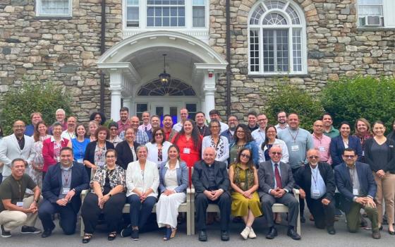 Large group assembled for portrait in front stone building. 