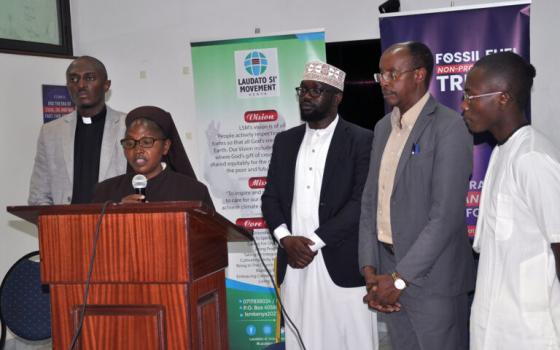 The presenters stand behind Sister Wangare who speaks at podium.