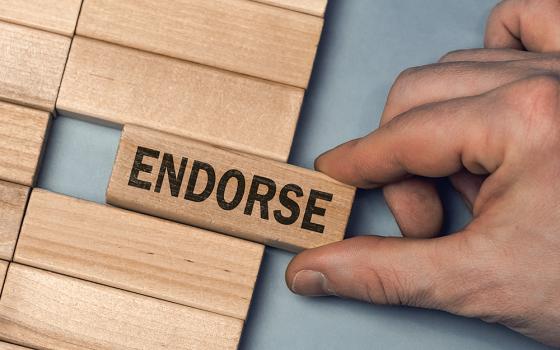 A hand pulls out a wooden block with the word ENDORSE on it (Dreamstime/Astiphoto13)