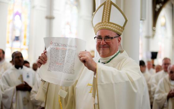 Archbishop Richard Henning displays the papal bull on his appointment to head the Archdiocese of Boston from Pope Francis during his installation Mass at the Cathedral of the Holy Cross, Oct. 31 in Boston. (OSV News/The Pilot/Gregory L. Tracy)