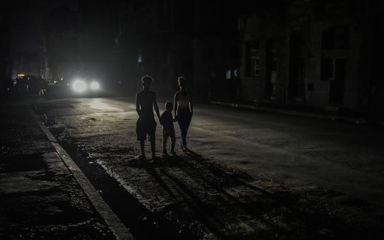Residents are illuminated by the headlights of a car during a blackout after a major power plant failed Oct. 18 in Havana, Cuba. (AP photo/Ramon Espinosa, file)