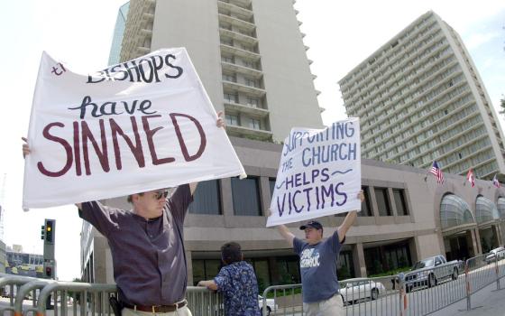 Protestors hold signs.