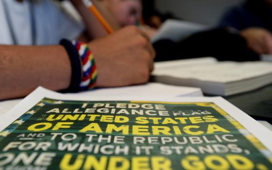 A copy of the Pledge of Allegiance rests on a desk next to an immigrant in a writing class at the U.S. government's holding center for migrant children in Carrizo Springs, Texas, July 9, 2019. (CNS/Eric Gay, pool via Reuters)