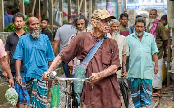 Maryknoll Fr. Bob McCahill walks his bike in May 2023 in Srinagar, Bangladesh, where he lives and serves the poor. (Paul Jeffrey)