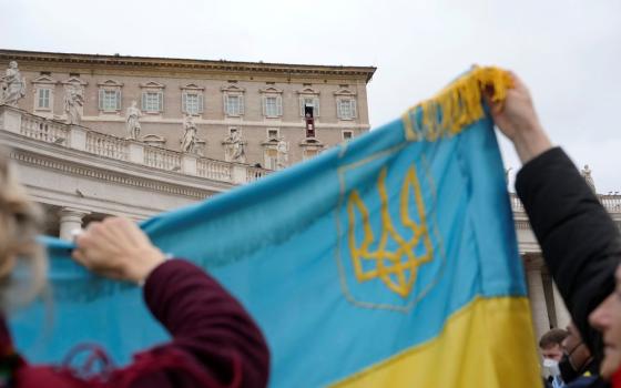 Ukrainian faithful hold their national flag as Pope Francis delivers the Angelus noon prayer from his studio window overlooking St. Peter's Square, at the Vatican, Feb. 20. (AP/Gregorio Borgia)