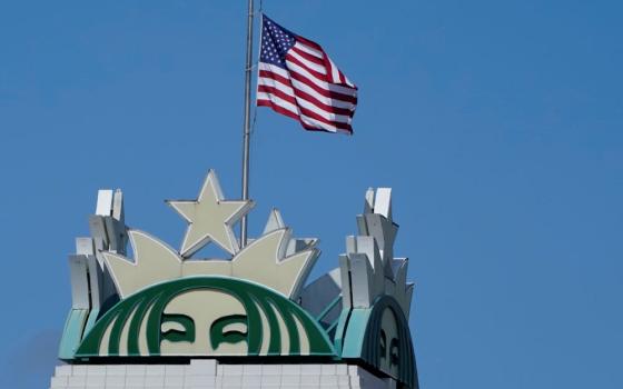 The U.S. flag flies above the Starbucks mermaid logo April 26, 2021, at the coffee company's corporate headquarters in Seattle. (AP/Ted S. Warren)