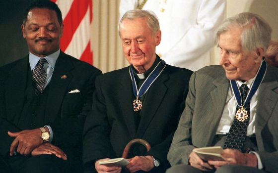 Msgr. George Higgins, center, smiles after receiving the nation's highest civilian honor, the Presidential Medal of Freedom, from President Bill Clinton in 2000. He was recognized for his lifelong commitment to workers' rights. (CNS)