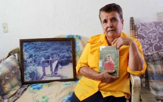 Guadalupe Lara in her home in Guadalajara, Mexico, with a copy of her memoir. A framed photograph of the historic Arcediano Bridge, which was destroyed during dam construction, rests at her side. (Tracy L. Barnett)