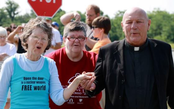 Oblate Fr. Carl Kabat, right, holds the hand of organizer Jane Stoever, left, as they lead protesters across the property line at the National Nuclear Security Administration's Kansas City Plant July 13, 2013, in Kansas City, Missouri. 