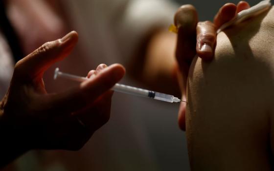 A medical worker administers a dose of the Pfizer BioNTech coronavirus vaccine Sept. 14 at a vaccination center in Nantes, France. (CNS/Reuters/Stephane Mahe)