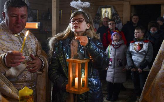 A girl holds a candle during a Christmas service at the Ukrainian Greek Catholic Church of the Holy Prophet Elijah in Kramatorsk, not far from a front line with Russia-backed separatists in eastern Ukraine, Dec. 25, 2021. (AP/Andriy Andriyenko)