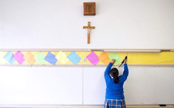 This July 18, 2012, file photo shows a student stapling colored paper to the wall of a classroom after summer school at Our Lady of Lourdes in Los Angeles. (AP Photo/Grant Hindsley)