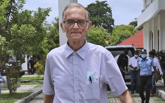 Richard Daschbach, a former missionary from Pennsylvania, is escorted by a police officer upon his arrival for a trial at a courthouse in Oecusse, East Timor on Feb. 23, 2021. (AP Photo/Raimundos Oki, File)