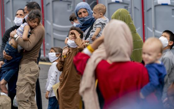 People evacuated from Afghanistan step off a bus as they arrive at a processing center Aug. 23 in Chantilly, after arriving on a flight at Dulles International Airport. (AP/Andrew Harnik)