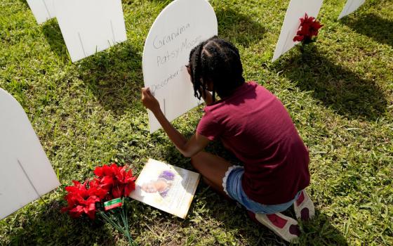 Kyla Harris, 10, writes a tribute Nov. 24 to her grandmother Patsy Gilreath Moore, who died at age 79 of COVID-19, at a symbolic cemetery created to remember and honor lives lost to COVID-19 in the Liberty City neighborhood of Miami. (AP/Lynne Sladky)