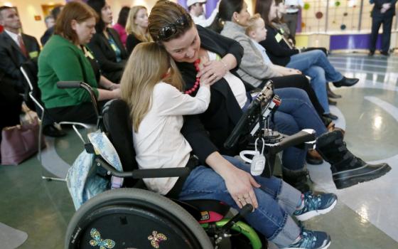 Eight-year-old Abigail Gabriel, center, hugs her mother, Erin, as Pennsylvania Department of Human Services Acting Secretary Teresa Miller talks about the Children's Health Insurance Program, CHIP, on Dec. 7, 2017, in Pittsburgh. (AP Photo/Keith Srakocic)