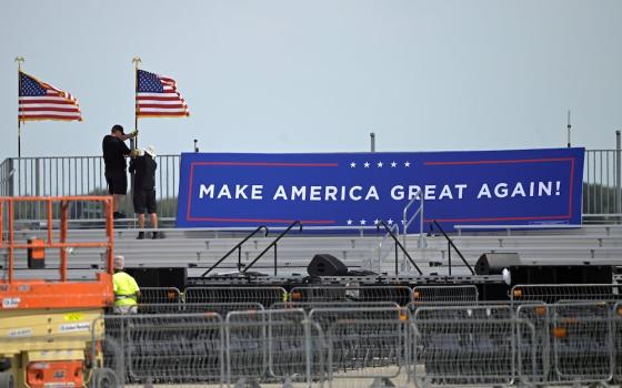 Following President Donald Trump's announcement he tested positive for the coronavirus disease, workers in Sanford, Florida, pull down signage at Orlando Sanford International Airport where the president was to have a rally Oct. 2. (CNS/Reuters/Phelan Ebe