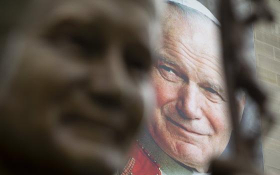 A banner of St. John Paul II is seen behind a sculpture of him May 16, 2018, at the St. John Paul II National Shrine in Washington. (CNS photo/Tyler Orsburn)