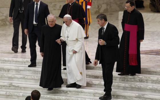 Pope Francis is assisted by Fr. Leonardo Sapienza, an official of the Prefecture of the Papal Household, as he walks down stairs during his general audience in Paul VI hall at the Vatican Jan. 18, 2017. (CNS/Paul Haring)